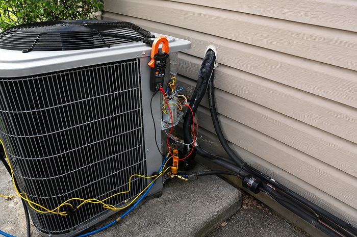 Technician checking an outdoor AC unit during maintenance